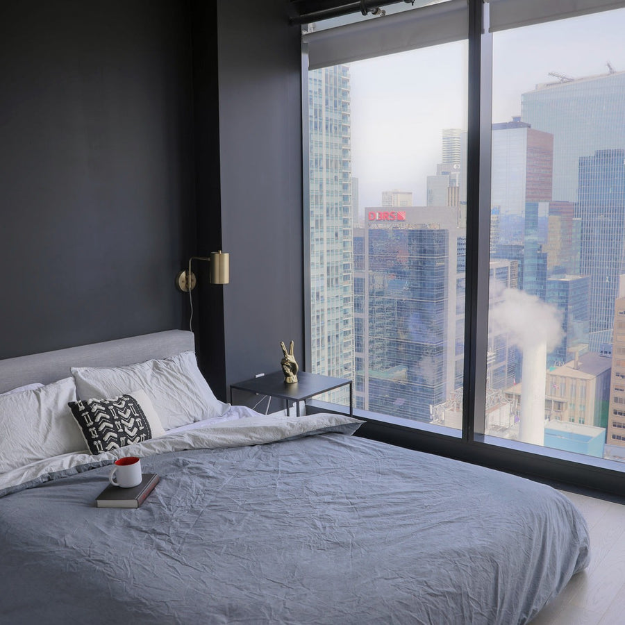 A dark bedroom with a city view at night